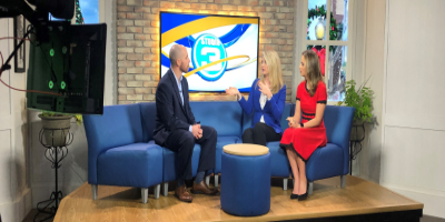 man being interviewed by two women on local news set